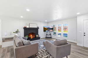 Living room featuring a brick fireplace, light wood-type flooring, and recessed lighting