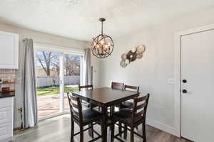 Dining room with light wood-style flooring, a textured ceiling, and suspended lighting