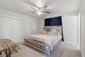 Carpeted bedroom featuring two closets and ceiling fan