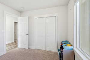 Bedroom with light colored carpet and a closet