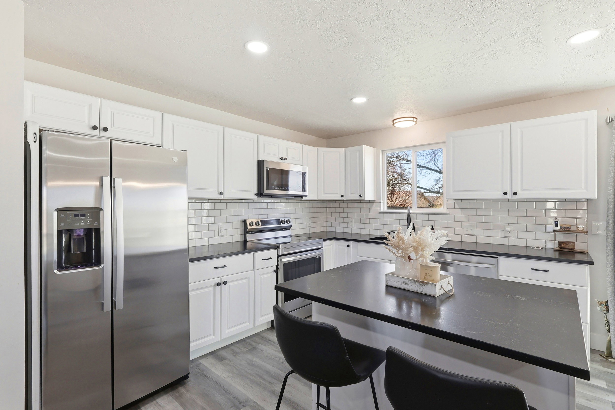 Kitchen featuring stainless steel appliances, light wood-style floors, white cabinets, a kitchen breakfast bar, and recessed lighting