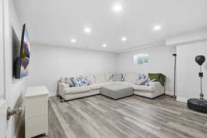 Living room with light wood-style flooring and recessed lighting