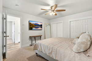 Bedroom with multiple closets, a ceiling fan, and light colored carpet