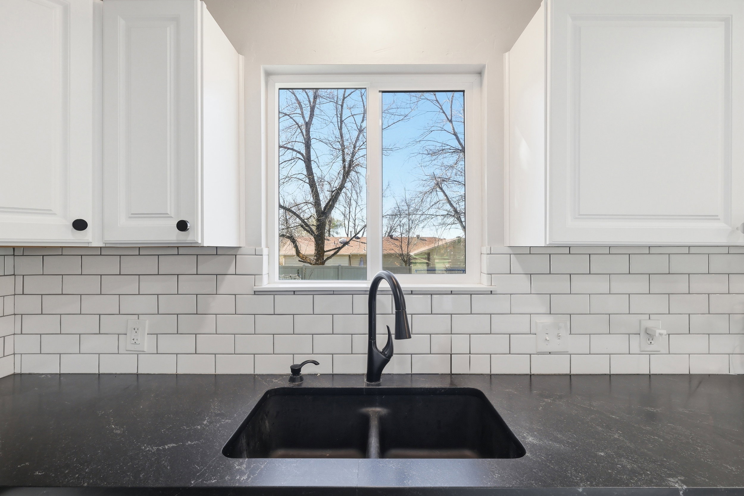 Kitchen featuring white cabinetry and dark stone counters