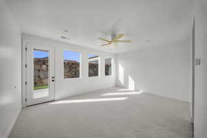 Unfurnished room featuring ceiling fan, light carpet, and plenty of natural light