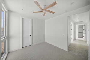Carpeted empty room featuring a ceiling fan and baseboards