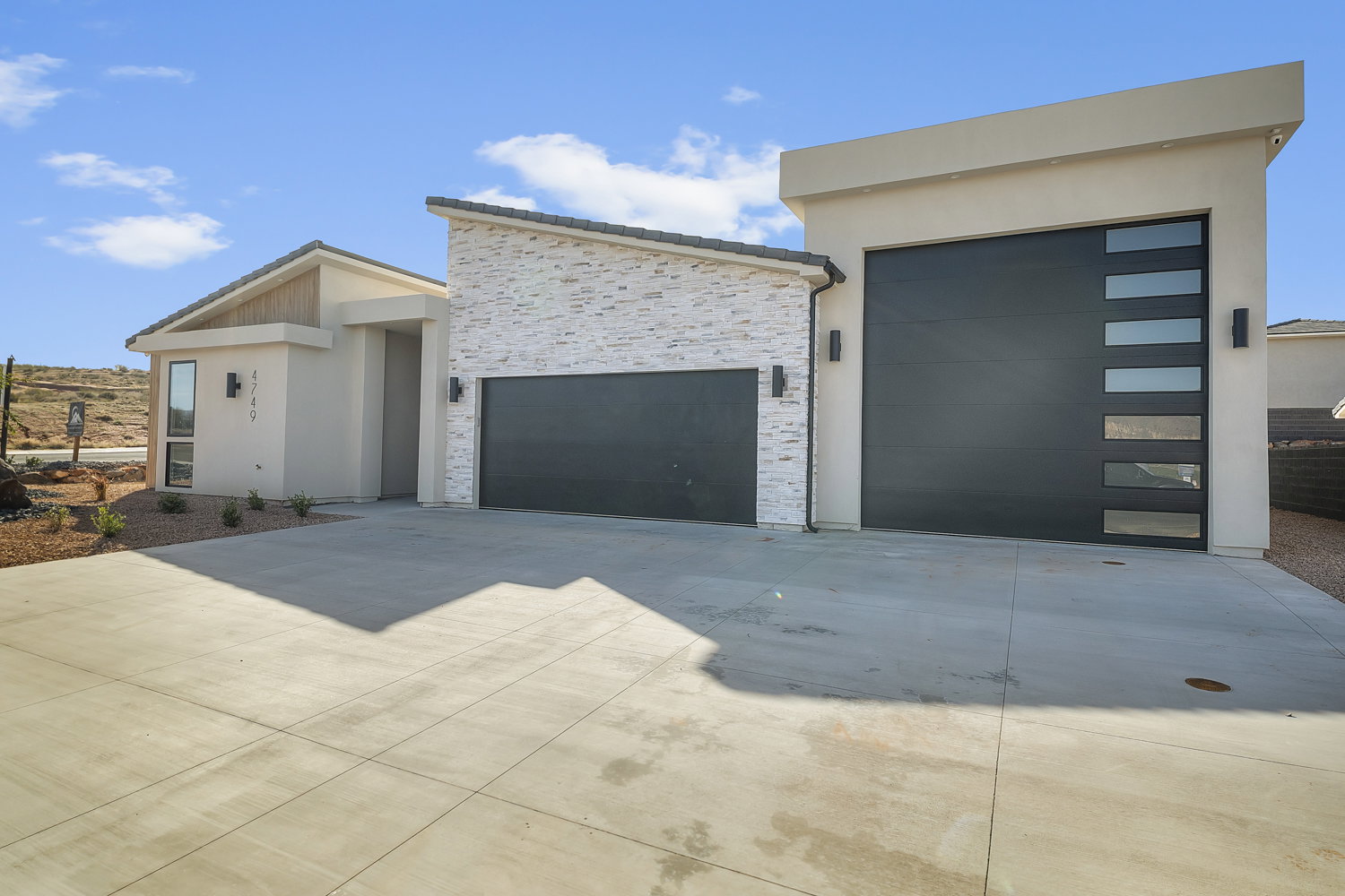 Contemporary home with concrete driveway, a garage, stucco siding, and stone siding