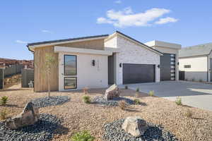 Modern home featuring a garage, stone siding, driveway, and an outdoor fire pit