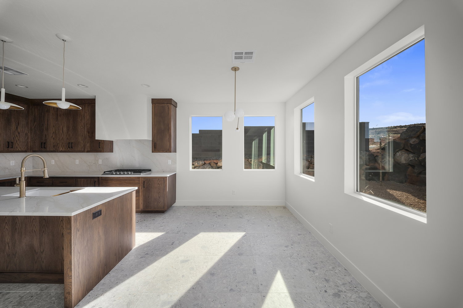 Kitchen featuring light stone countertops, tasteful backsplash, pendant lighting, stainless steel gas stovetop, and dark wood finish cabinetry