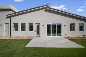 Back of house featuring a yard, a patio, and stucco siding
