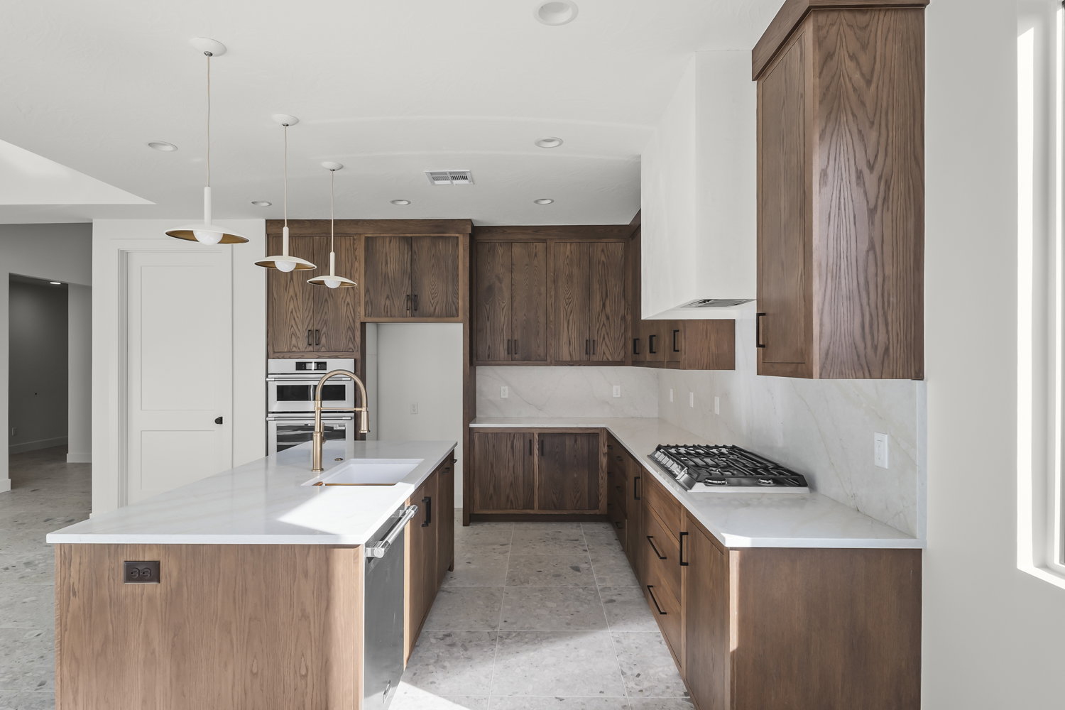 Kitchen featuring a kitchen island with sink, light stone countertops, decorative light fixtures, and backsplash