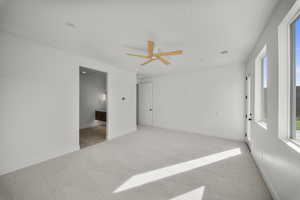 Empty room with light colored carpet and a ceiling fan