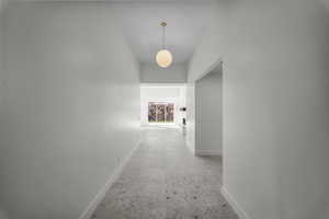 Hallway with baseboards and a high ceiling