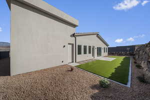 Rear view of property with stucco siding, a fenced backyard, and a patio