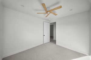 Spare room featuring light carpet and a ceiling fan