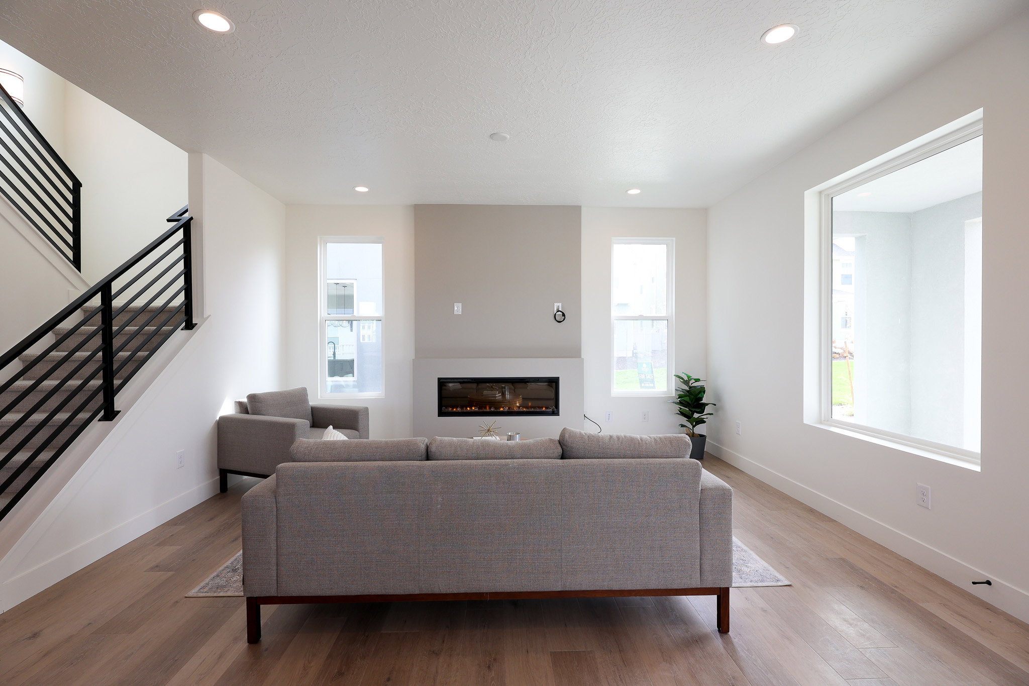 Living area with light wood-style floors, a glass covered fireplace, and recessed lighting