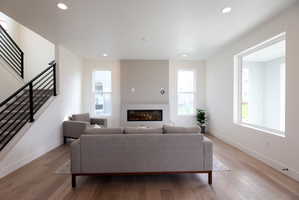 Living area with light wood-style floors, a glass covered fireplace, and recessed lighting