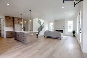 Kitchen featuring open floor plan, a breakfast bar, decorative light fixtures, an island with sink, and wood finish cabinetry