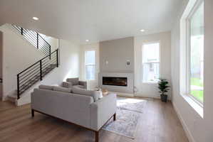 Living room featuring wood finished floors, a glass covered fireplace, and recessed lighting