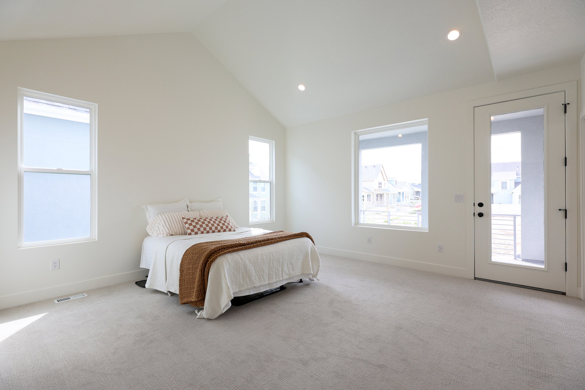 Primary bedroom with vaulted ceiling and access to private balcony