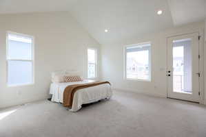 Primary bedroom with vaulted ceiling and access to private balcony