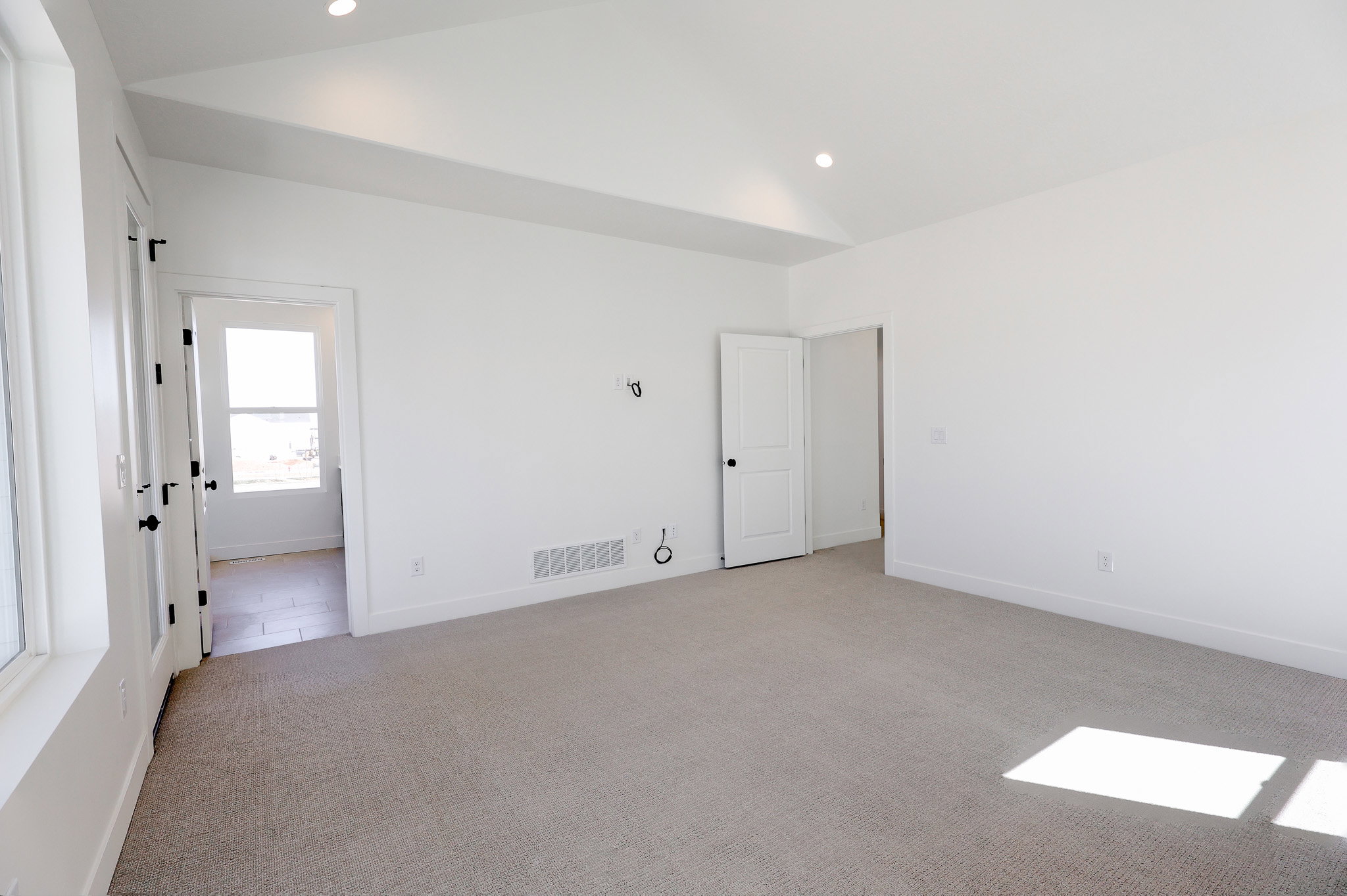 Primary bedroom with vaulted ceiling and access to private balcony