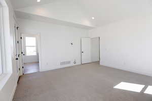 Primary bedroom with vaulted ceiling and access to private balcony