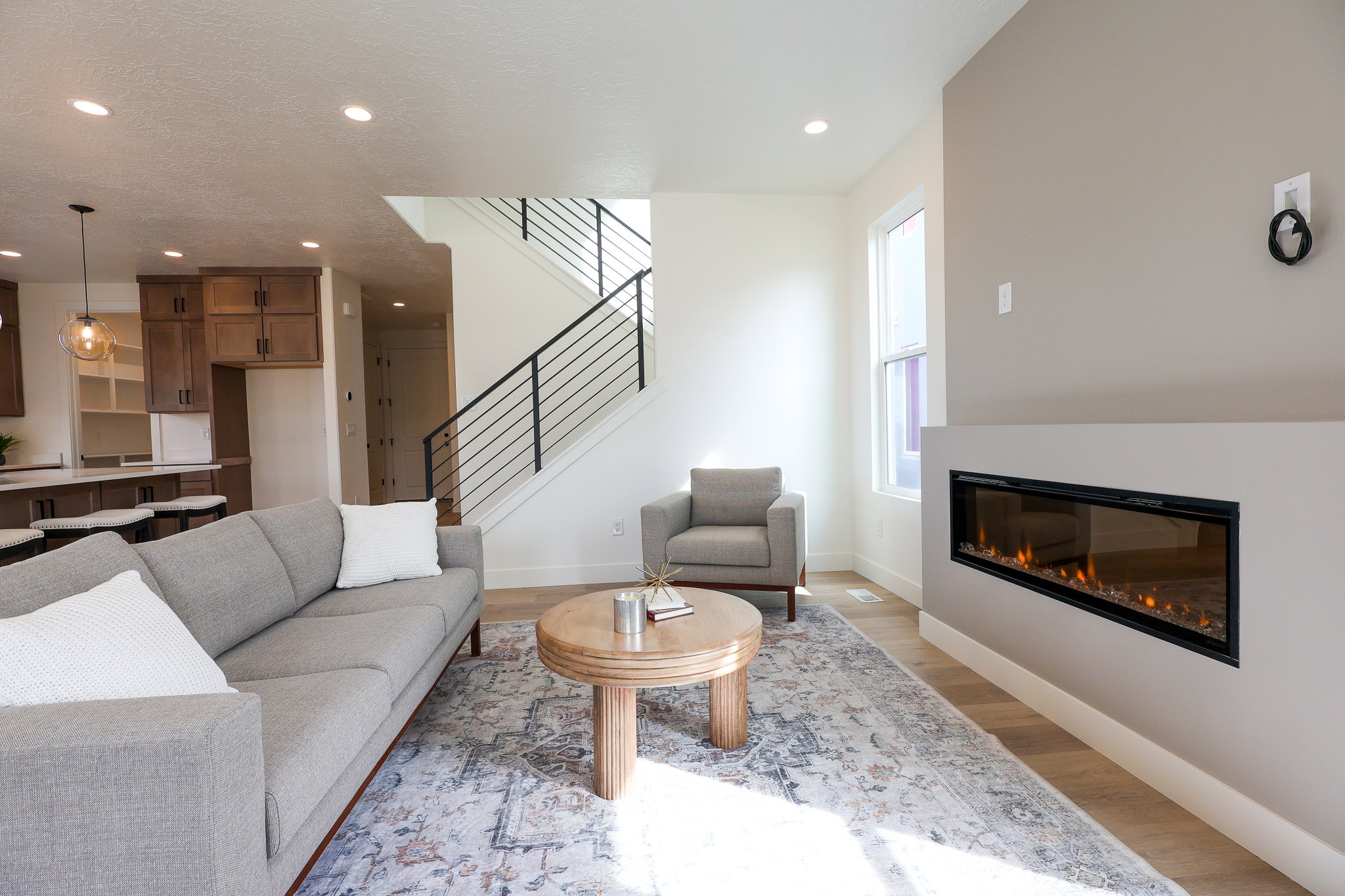 Living room with a glass covered fireplace, wood finished floors, and recessed lighting