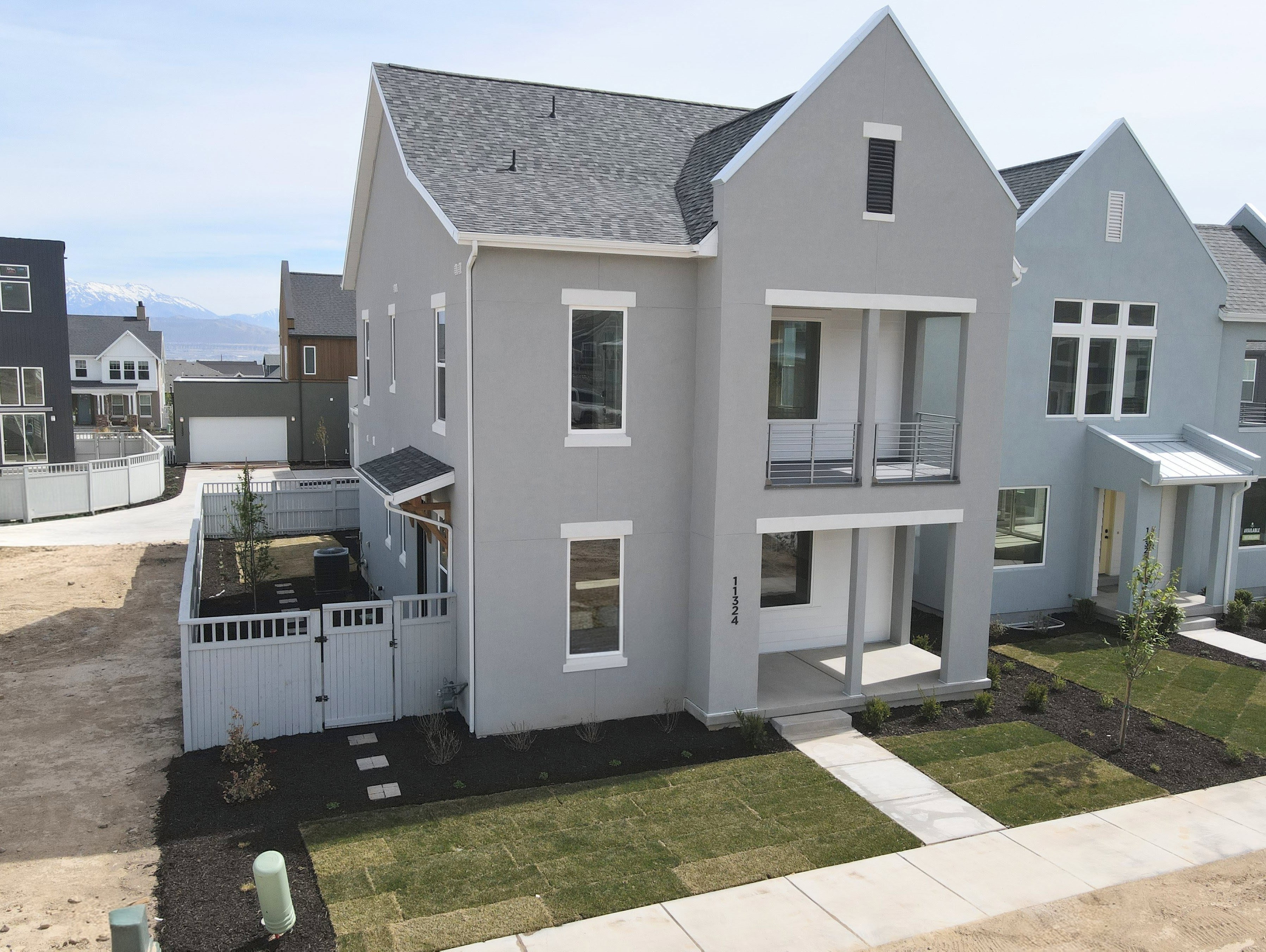 View of front facade with a gate, roof with shingles, stucco siding, a residential view, and a balcony