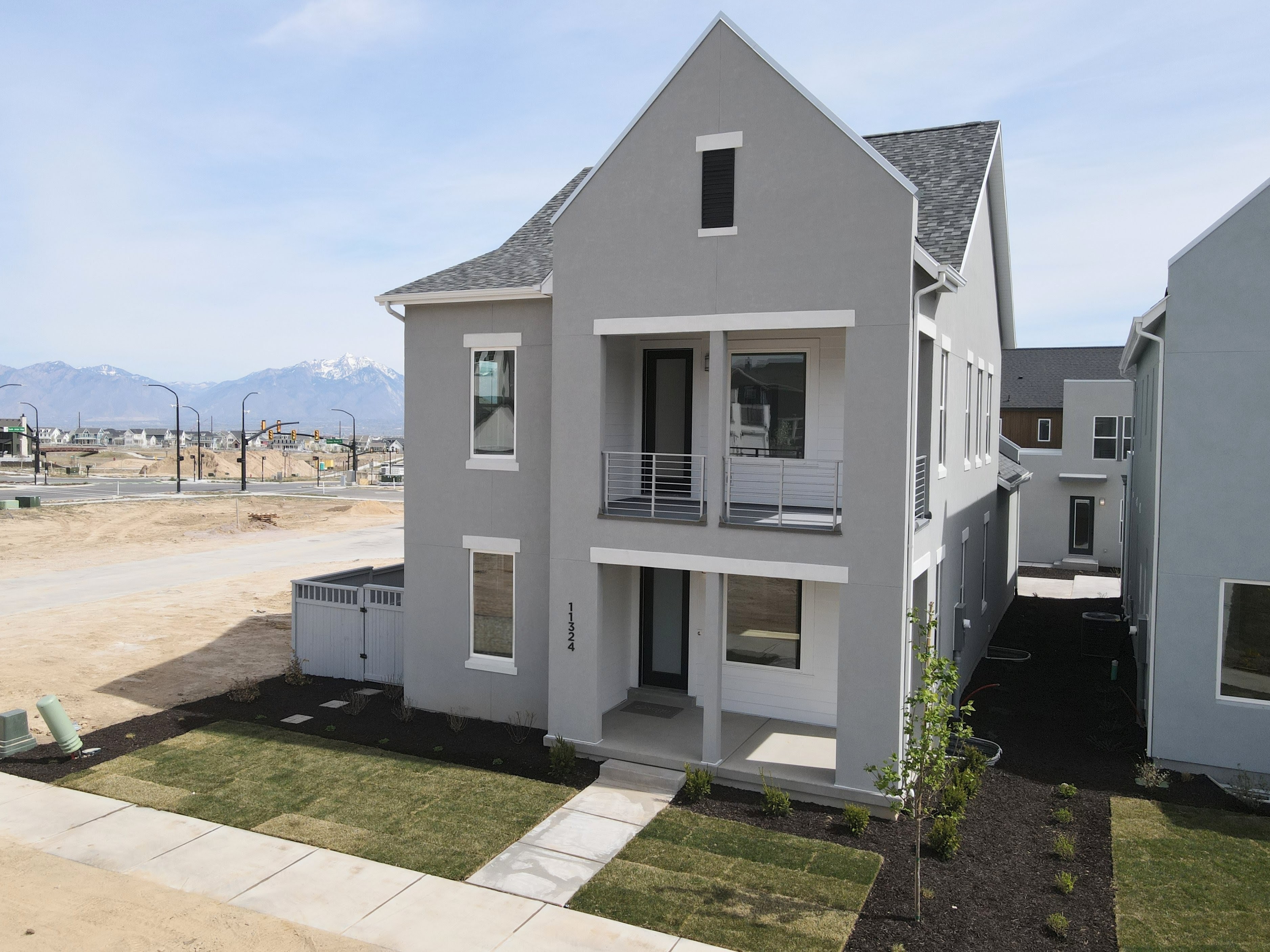 Contemporary home featuring a shingled roof, a balcony, stucco siding, a front yard, and covered porch