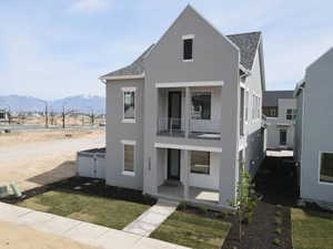 Contemporary home featuring a shingled roof, a balcony, stucco siding, a front yard, and covered porch