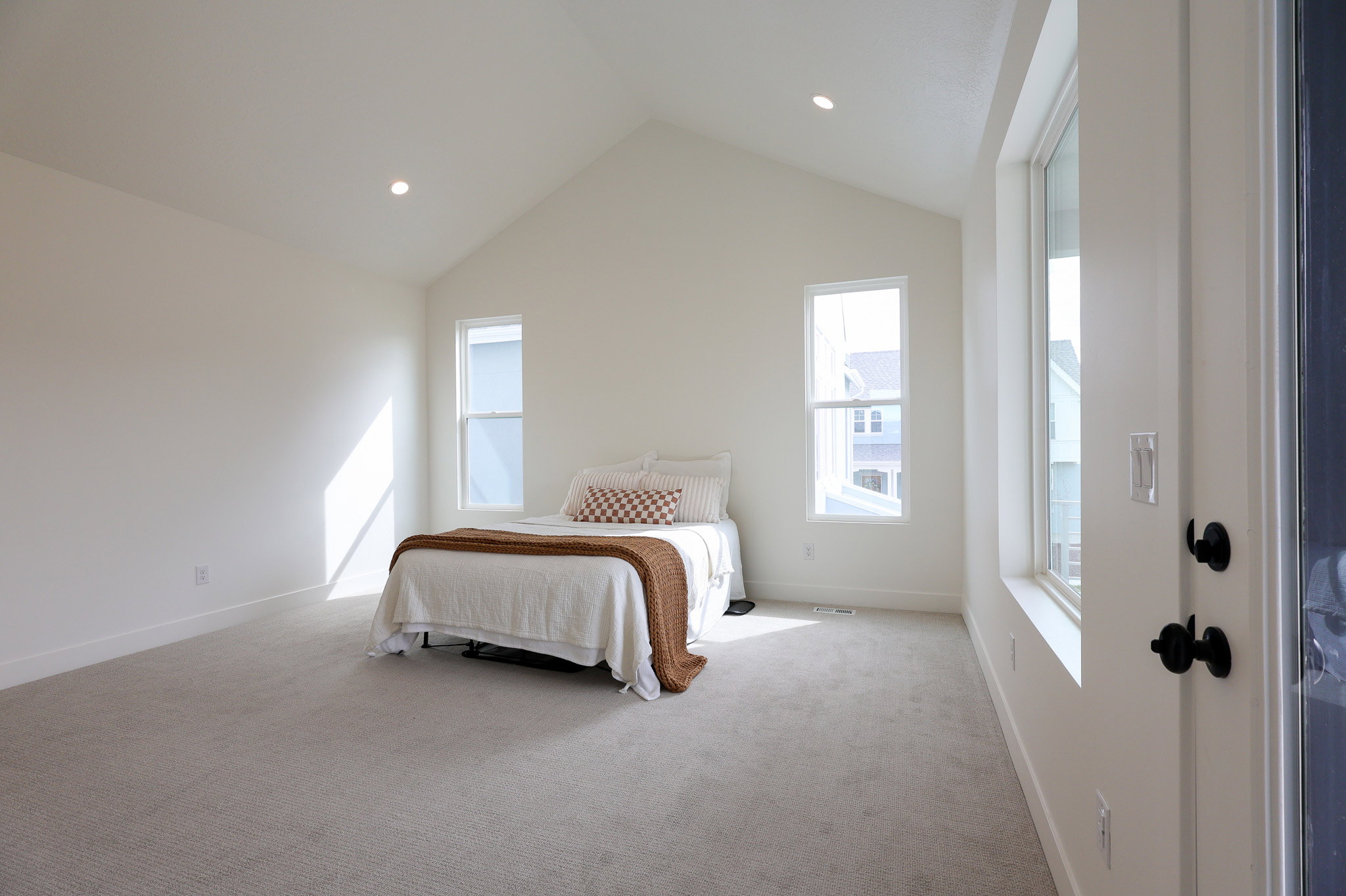 Primary bedroom with vaulted ceiling and access to private balcony
