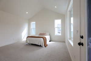 Primary bedroom with vaulted ceiling and access to private balcony