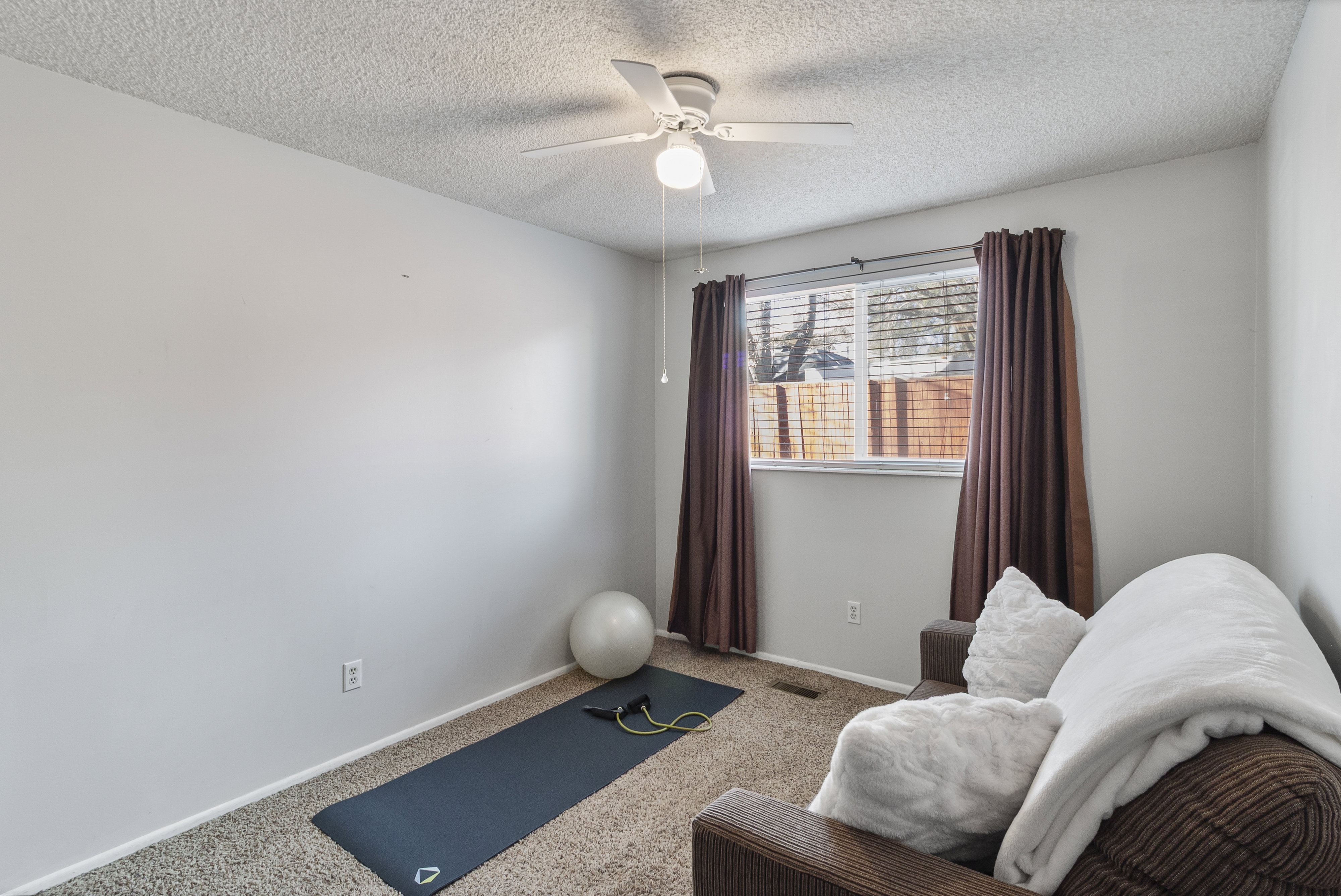 Workout room featuring carpet flooring, a ceiling fan, and a textured ceiling