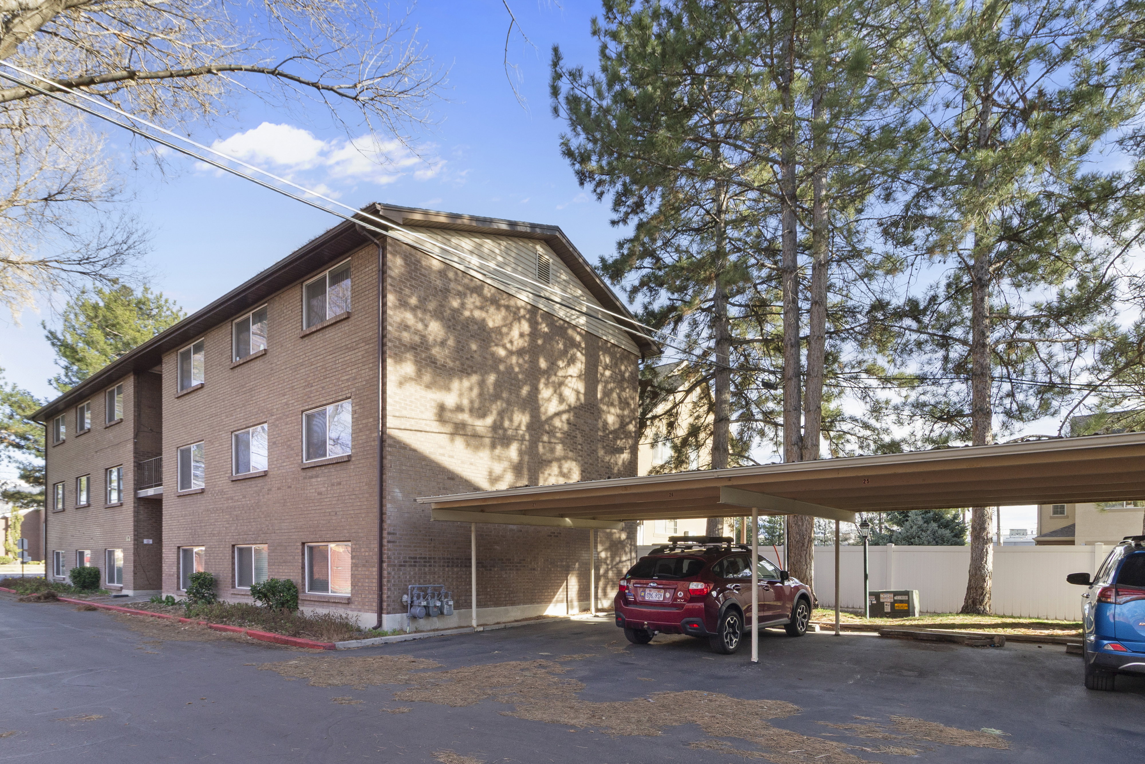 View of apartment building / complex featuring covered parking