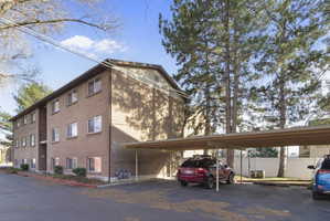 View of apartment building / complex featuring covered parking