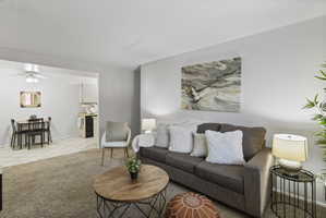 Living area featuring light colored carpet and a ceiling fan