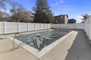 View of swimming pool featuring patio surround and a fenced backyard