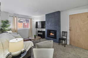Living area with a premium fireplace and carpet