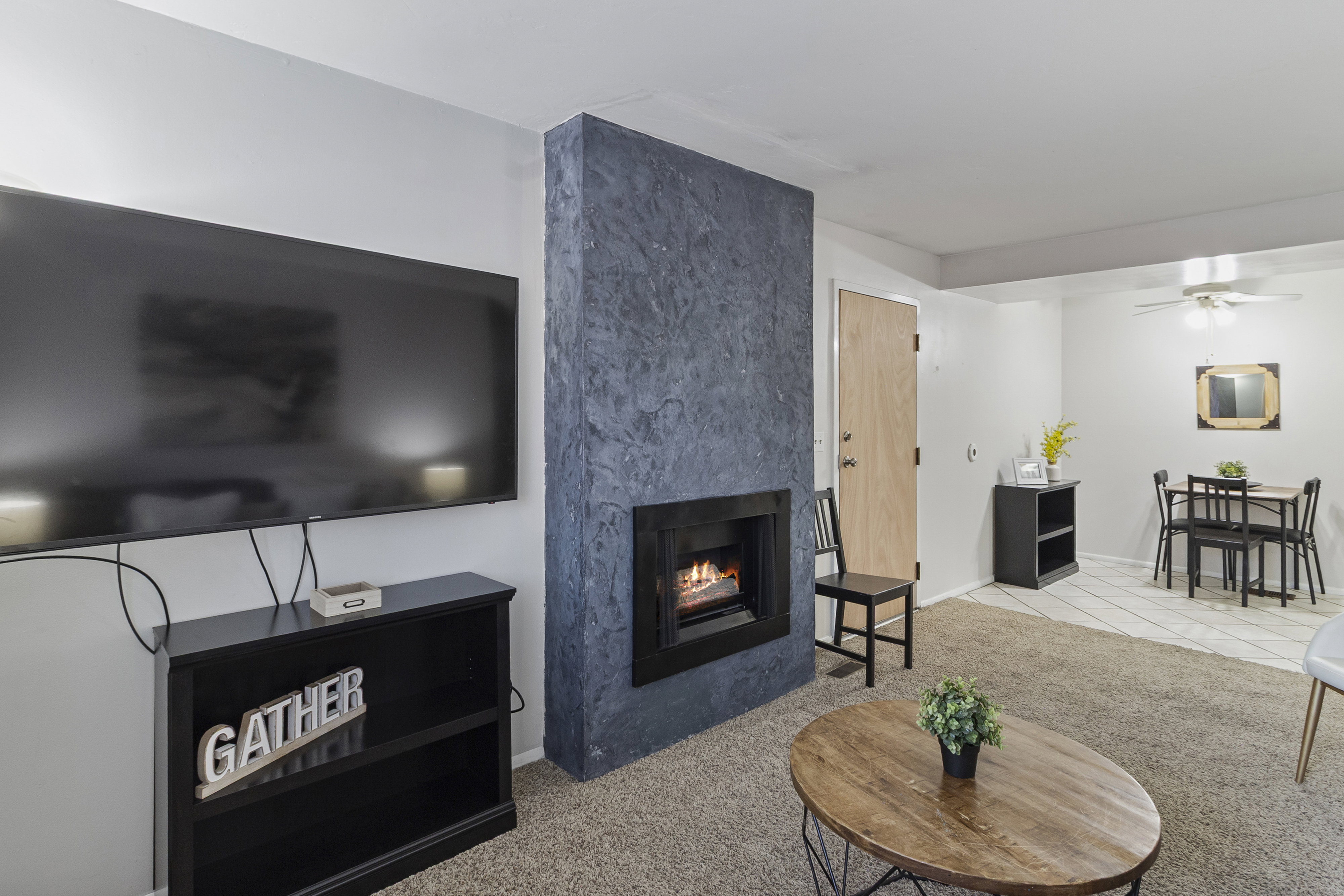 Living room featuring light colored carpet, a high end fireplace, and ceiling fan