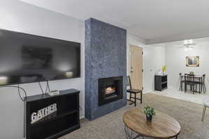 Living room featuring light colored carpet, a high end fireplace, and ceiling fan