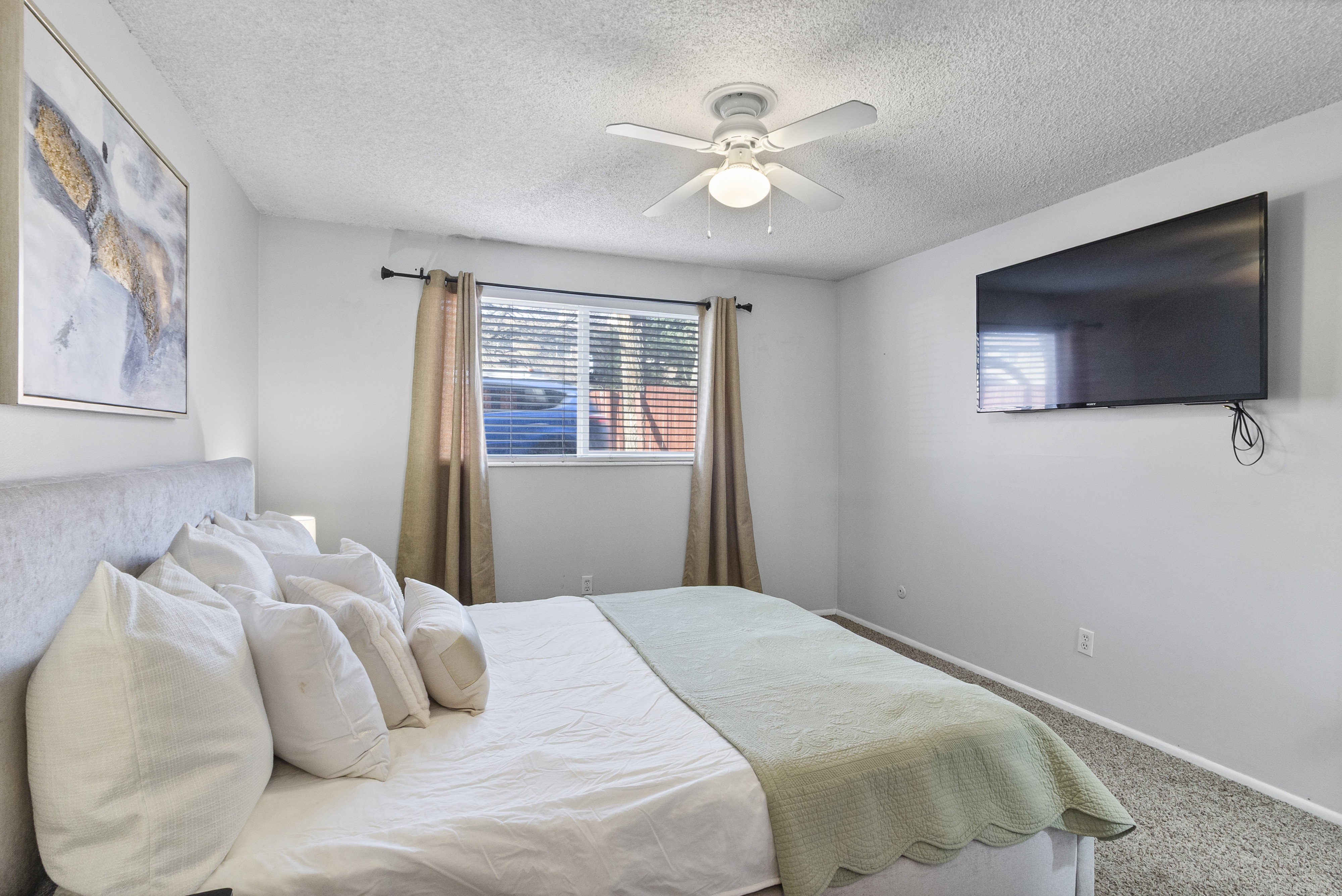 Carpeted bedroom featuring ceiling fan and a textured ceiling