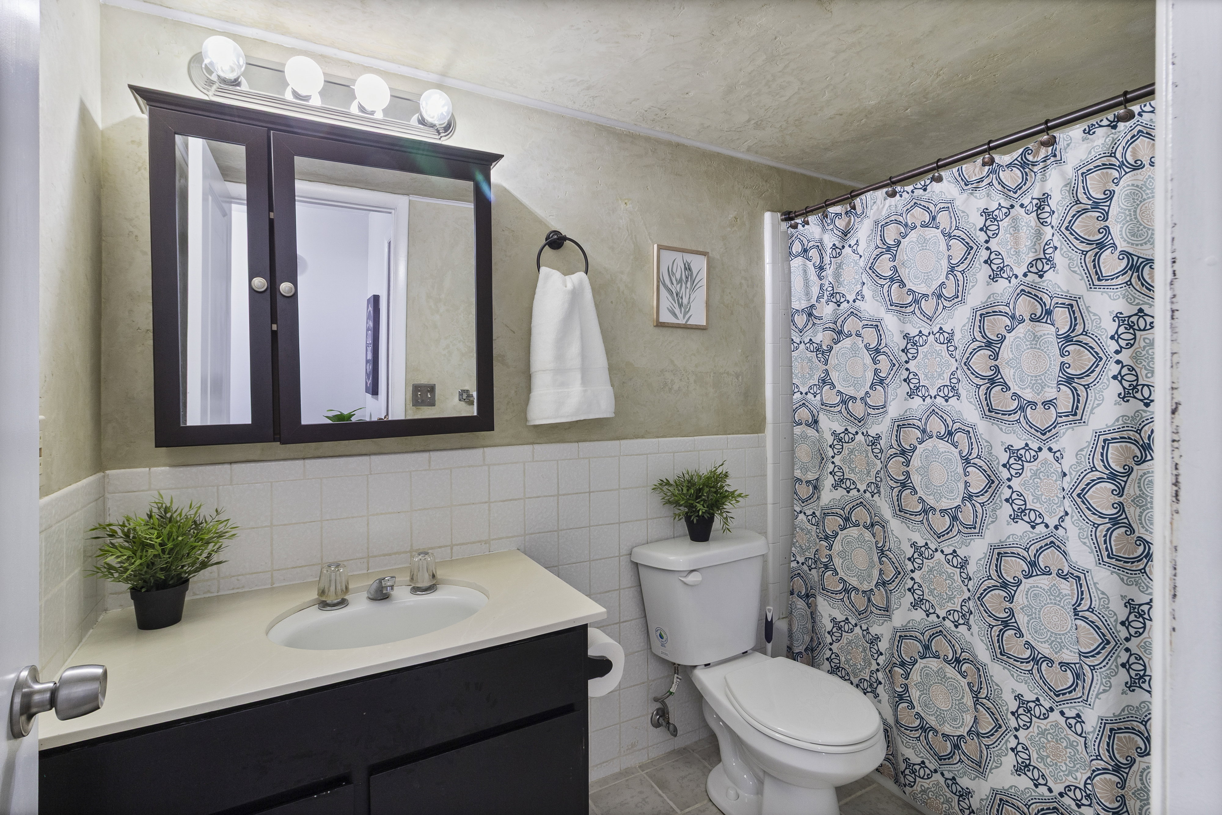 Bathroom with vanity, a shower with shower curtain, tile walls, and wainscoting
