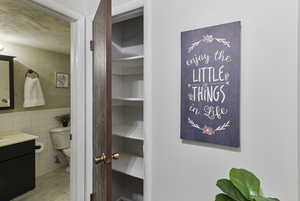 Bathroom view of vanity, tile walls, a closet, and a wainscoted wall