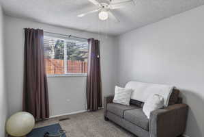 Living area with carpet floors, a textured ceiling, and a ceiling fan