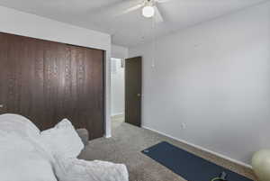 Bedroom featuring carpet flooring, a textured ceiling, a ceiling fan, and a closet