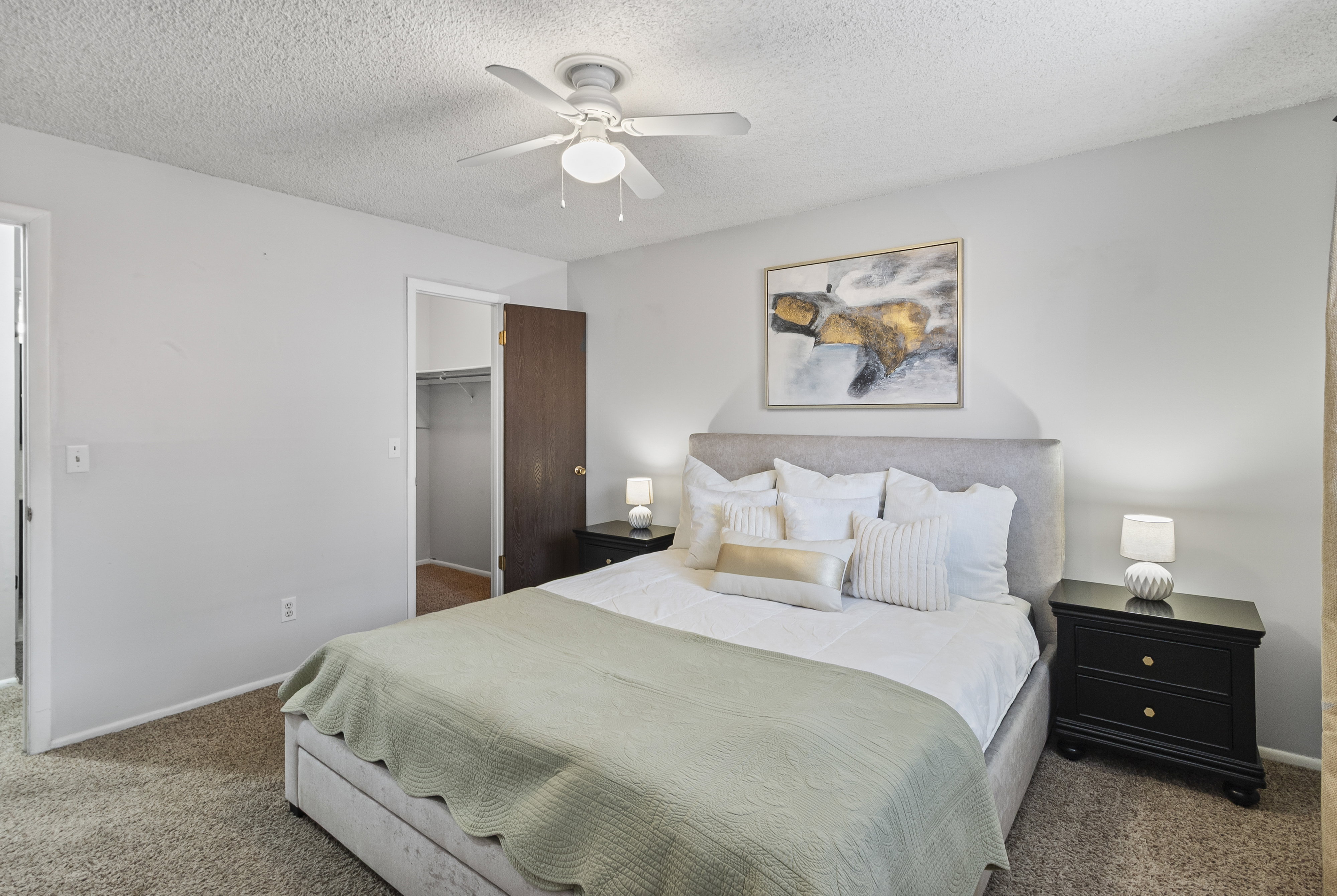 Carpeted bedroom featuring a spacious closet, a textured ceiling, and a ceiling fan