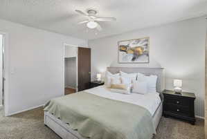 Carpeted bedroom featuring a spacious closet, a textured ceiling, and a ceiling fan