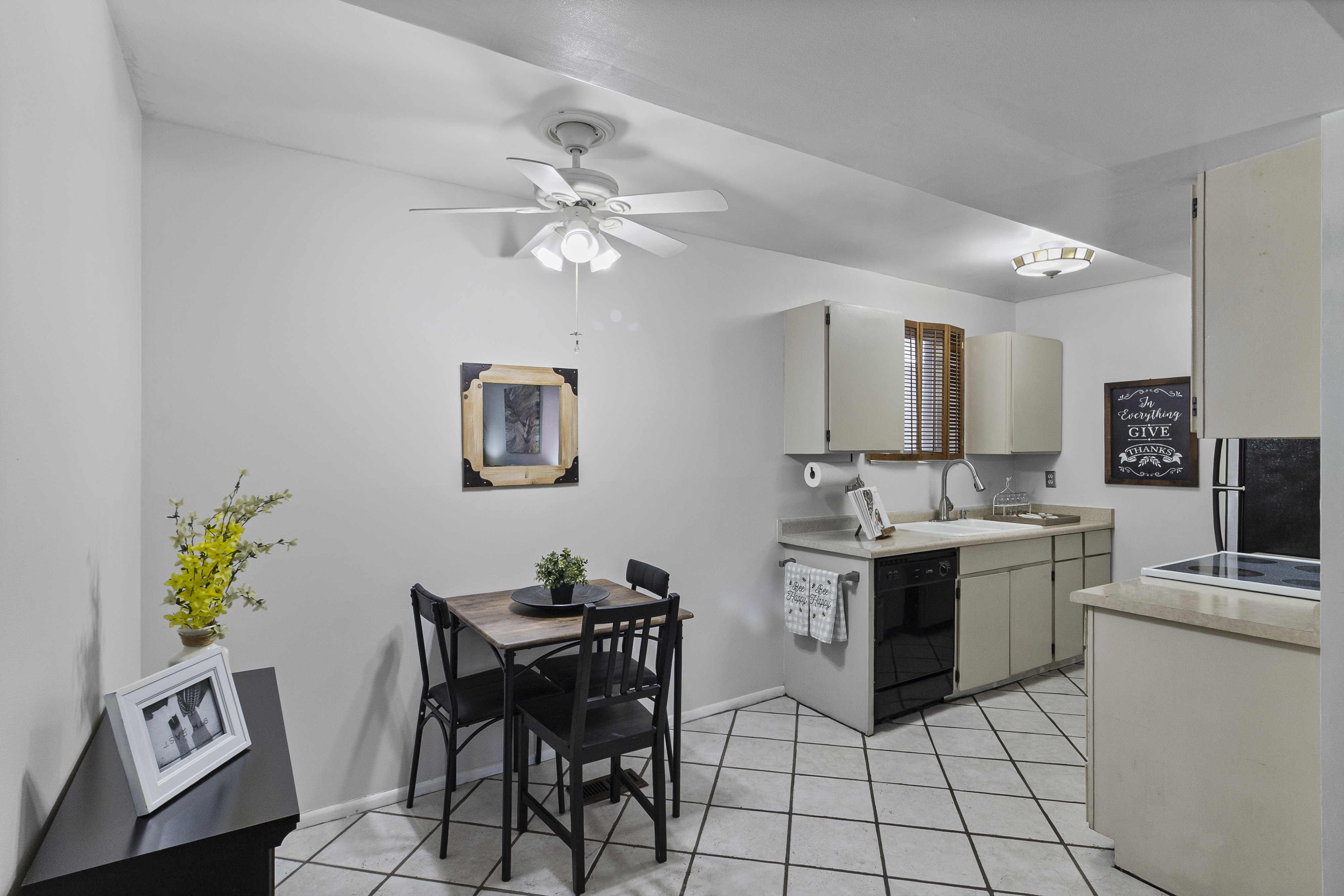 Kitchen with light countertops, a ceiling fan, freestanding refrigerator, dishwasher, and light tile patterned floors