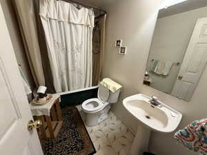 Full bathroom with toilet and shower / bath combination with curtain